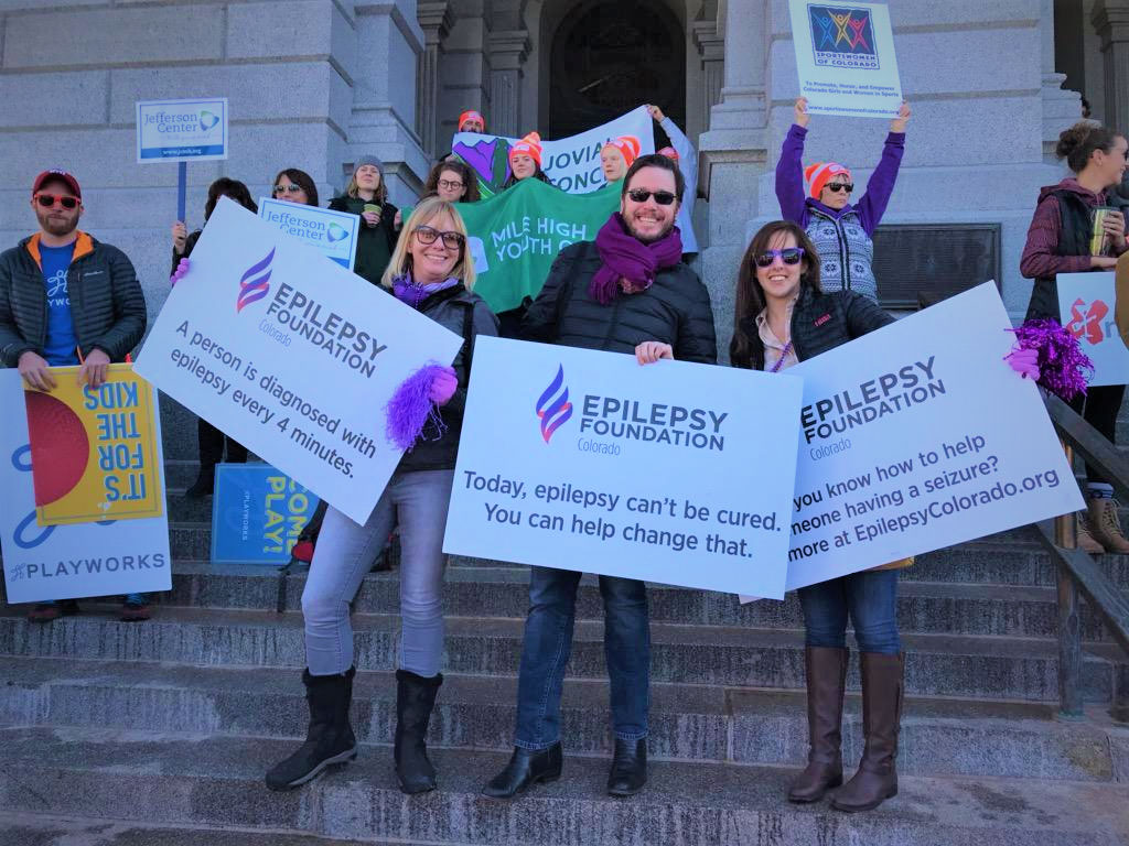 People holding signs for epilepsy awareness in front of the Colorado State Capitol