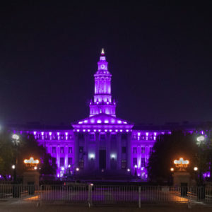 efcw-advocacy The Denver City and County Building lit up with purple lights