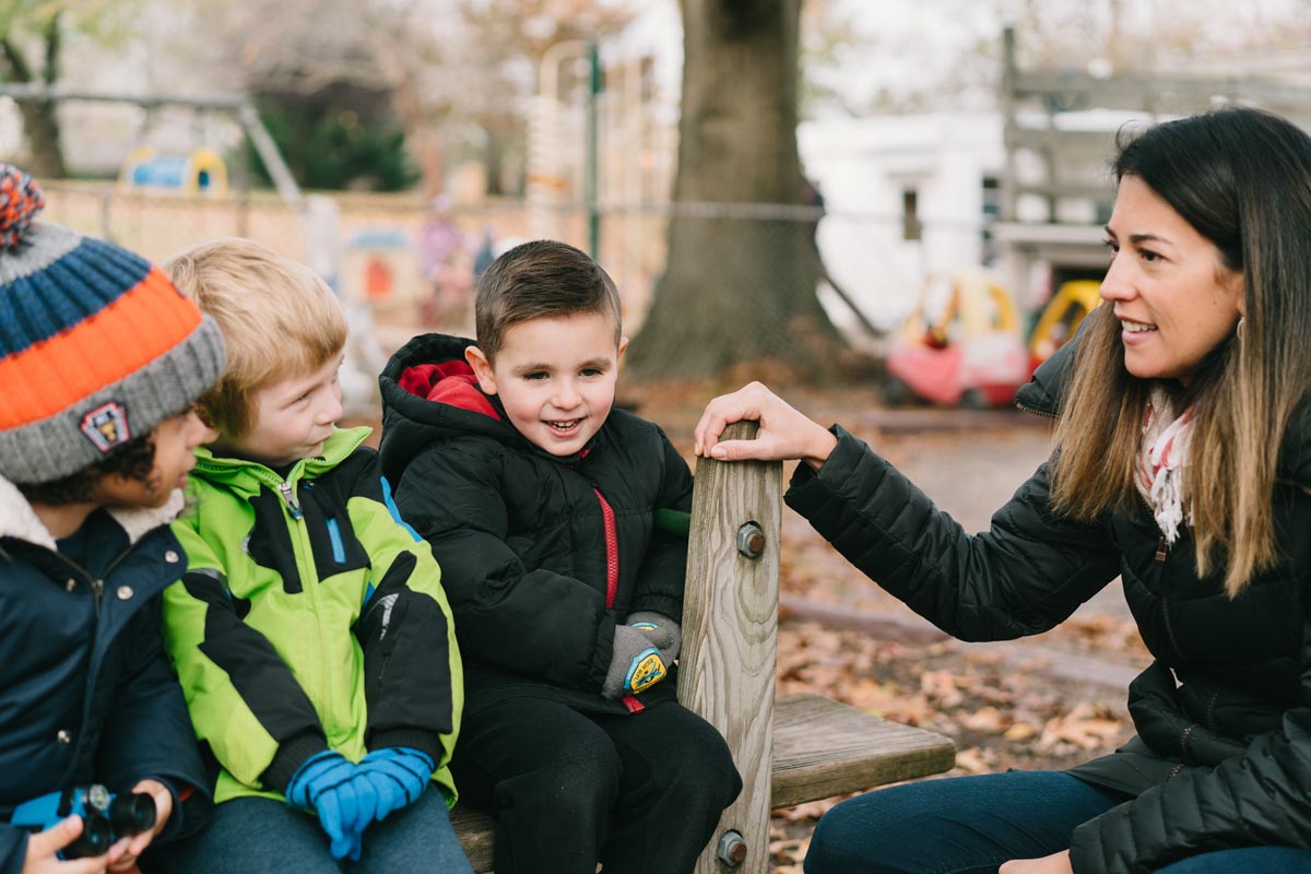 A teacher talks to elementary school students on a playground