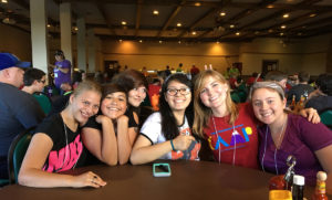 Teens sitting at a table together smiling